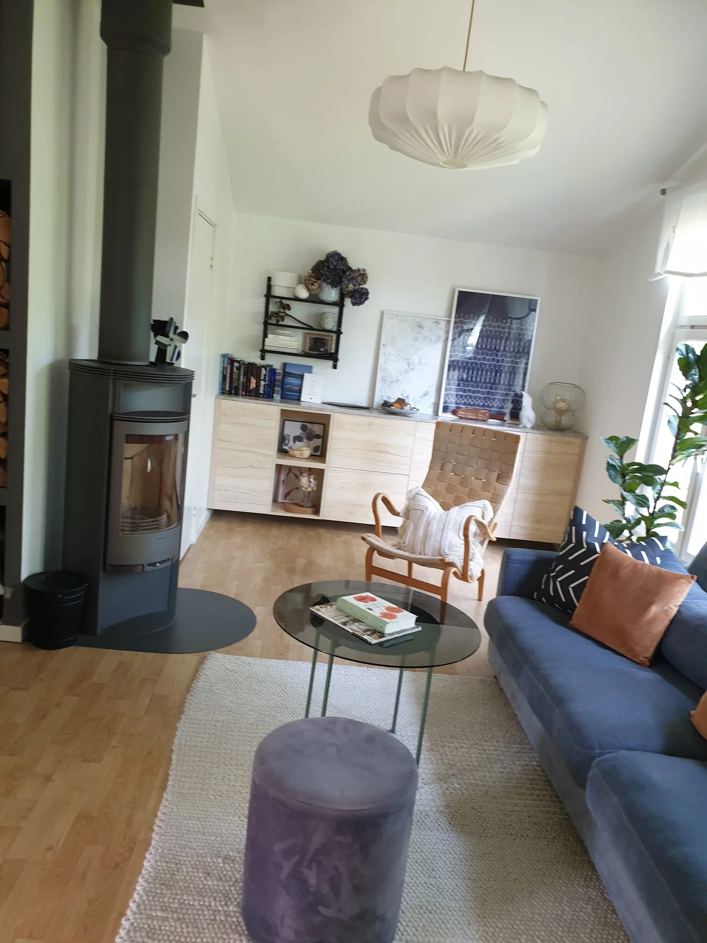 Vardagsrum med kamin, blå soffa, fåtölj och soffbord i glas